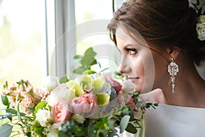 Bride with a bouquet waiting for the groom near the window