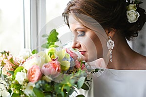 Bride with a bouquet waiting for the groom near the window