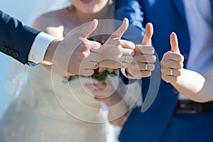 Bride, bridesmaid, groom and groomsman showing thumb up outdoors photo