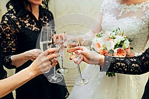 Bride and bridesmaids celebrate and drink champagne from glasses