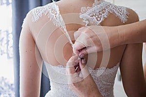 Bride buttoning wedding dress in the morning