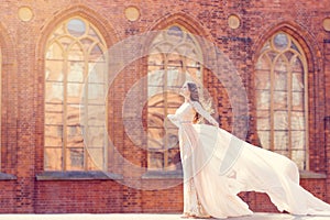 Bride on Church Background, Elegant Fashion Model in Long White Gown Beauty Portrait, Dress Waving on Wind photo