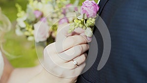 Bride cling buttonhole of pink roses on lapel of groom's jacket with pin