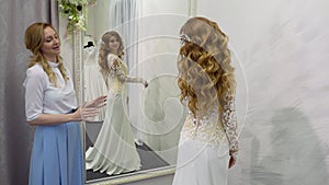 Bride at the clothes shop for wedding dresses she is choosing a dress and the designer is assisting her