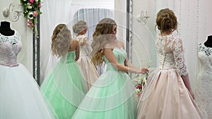 Bride at the clothes shop for wedding dresses she is choosing a dress and the designer is assisting her