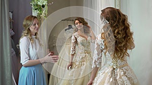 Bride at the clothes shop for wedding dresses she is choosing a dress and the designer is assisting her