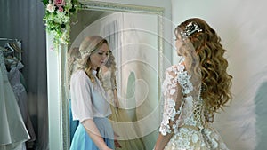 Bride at the clothes shop for wedding dresses she is choosing a dress and the designer is assisting her