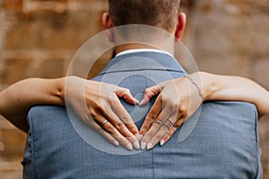 Bride creating a heart shape with her hands on the back of the groom