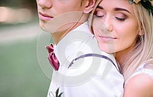 Bride daydreams on groom`s shoulder while hugging him from behind photo