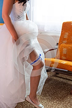 Bride dresses garter on the leg.