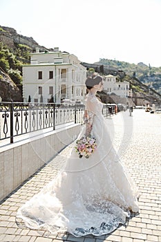 bride in elegant wedding dress posing outdoor with tender bouquet of flowers