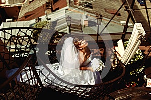 Bride enjoys summer sun standing on the spiral stairs on the roof