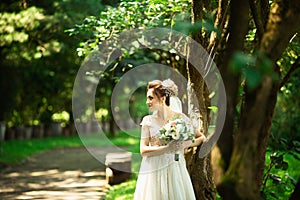 Bride in fashion wedding dress on natural background. A beautiful woman portrait in the park