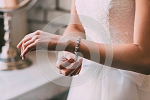 Bride fastens a bracelet. Wedding concept. Artwork. Soft focus on a hand