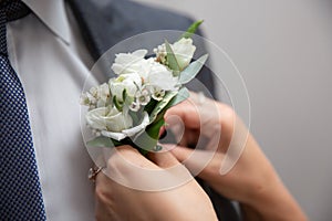 Bride fastens groom boutonniere to buttonhole