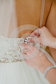 The bride fastens her dress. Close-up