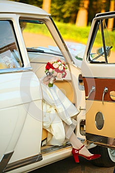 The bride gets out of the car in red shoes