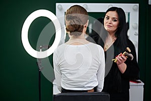 Bride getting ready for wedding. Professional make-up artist applying blush on female clients` face with big makeup brush. Work