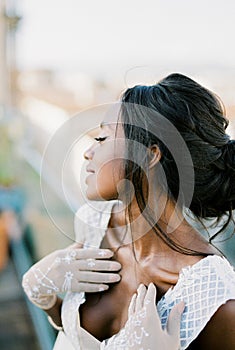 Bride in gloves touches her collarbones with her hands