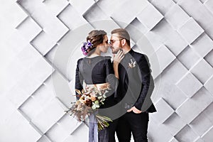 Bride and groom on the background gray squares in studio. Back view of bride, focus on groom. Wedding lovestory concept