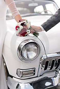 bride and groom on the background of a retro car. The bride's bouquet