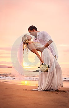 Bride and groom on beach at sunset