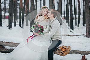 Bride and groom with a bouquet are posing in snowy forest. Winter wedding. Artwork