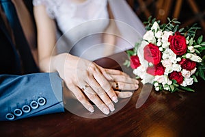 Bride and groom in a cafe. wedding bouquet of roses on a wooden table in a restaurant, bride and groom hold each other`s
