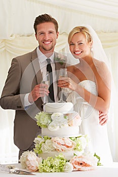 Bride And Groom With Cake Drinking Champagne At Reception