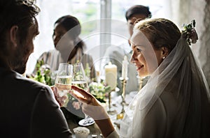 Bride and Groom Clinging Wineglasses Together at Wedding Reception photo