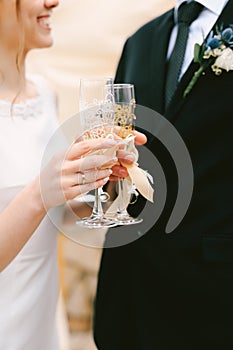 Bride and groom clink glasses of champagne. Close up