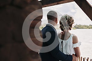 Bride and groom in a country house looking into the distance on lake