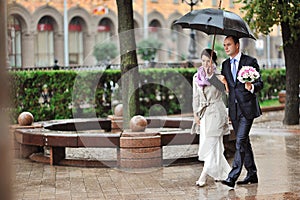 Bride and groom couple walking together in a rainy day