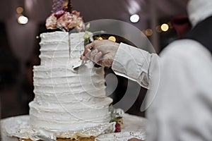 Bride and groom cut rustic wedding cake on wedding banquet with red rose and other flowers