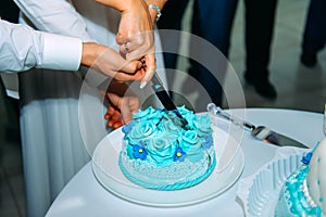 Bride and groom cut their wedding cake at wedding banquet. Hands cut beautiful cake during ceremony. Concept of wedding