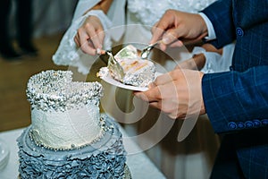 Bride and groom cut their wedding cake at wedding banquet. Hands cut beautiful cake during ceremony. Concept of wedding