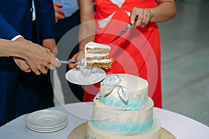 Bride and groom cut their wedding cake at wedding banquet. Hands cut beautiful cake during ceremony. Concept of wedding