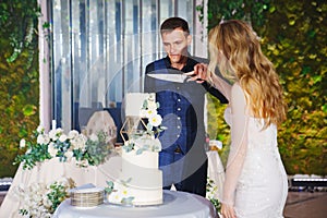 The bride and groom cut the wedding cake at the banquet.