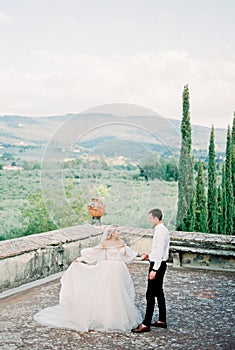 Bride and groom dance near the stone fence in the garden