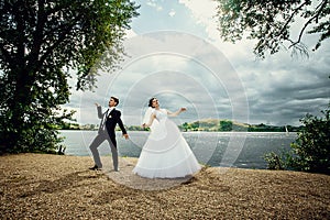 The bride and groom dance their merry wedding dance on the shore of the pond