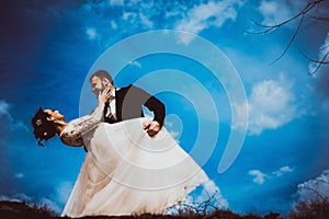Bride and groom dancing against a cloudy sky. Happy newlywed couple in love. Wedding day. The bride and groom are twenty-five