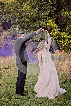 Bride and Groom dancing in forest with purple smoke