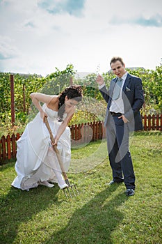 Bride and groom digs the soil on a kitchen garden.