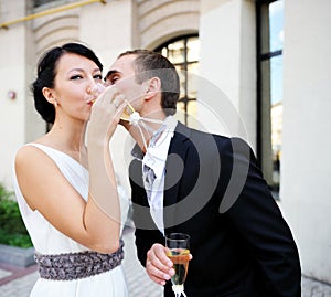 Bride and groom drinking champagne outdoors