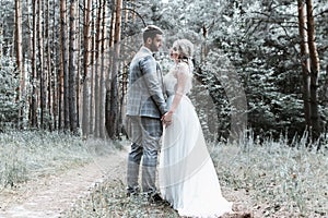 The bride and groom embrace in the forest on the wedding day. wedding ceremony. selective focus. film grain