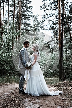 The bride and groom embrace in the forest on the wedding day. wedding ceremony. selective focus. film grain