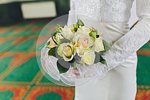 The bride and groom embrace and hold a wedding bouquet of pastel flowers, close-up.