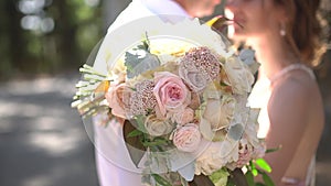 The bride and groom are embracing, the bride is holding a wedding bouquet in her hands, close-up