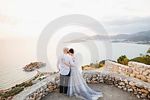 The bride and groom are embracing on the observation deck overlooking the island of Sveti Stefan