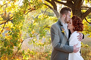 Bride and groom embracing. Romantic autumn outdoor setting.